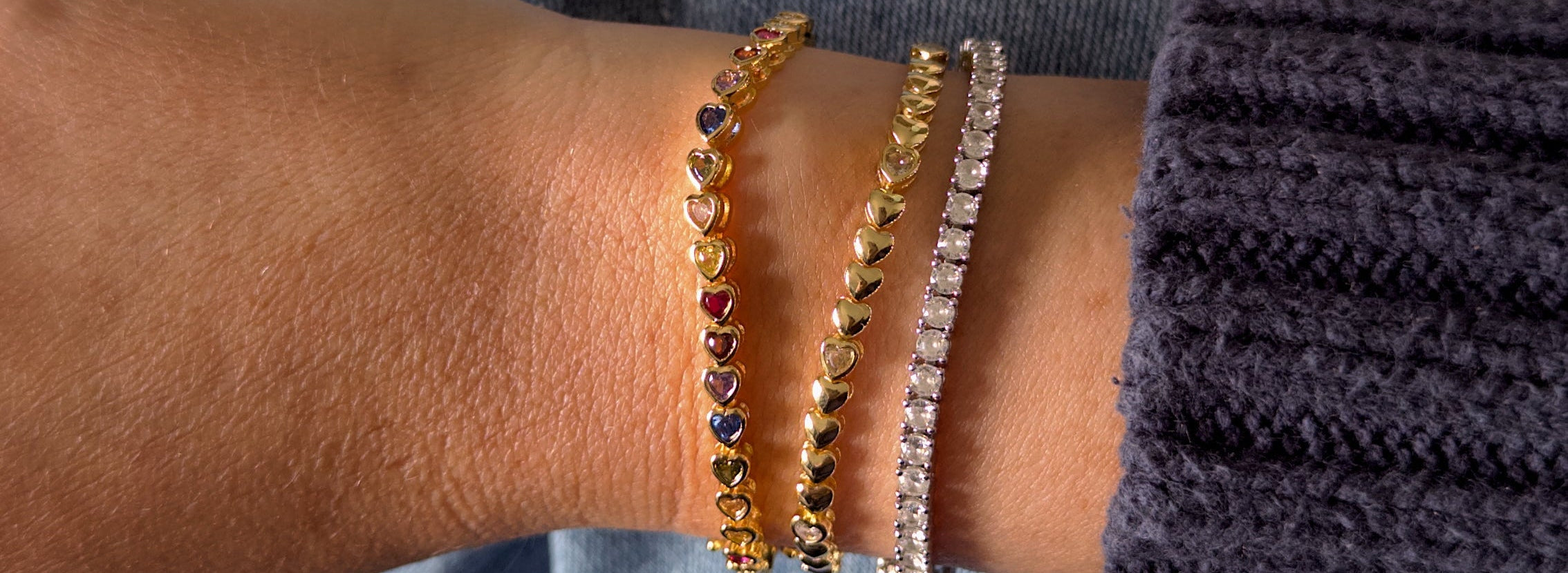 Close-up of a person's wrist wearing multiple bracelets on a blurred background